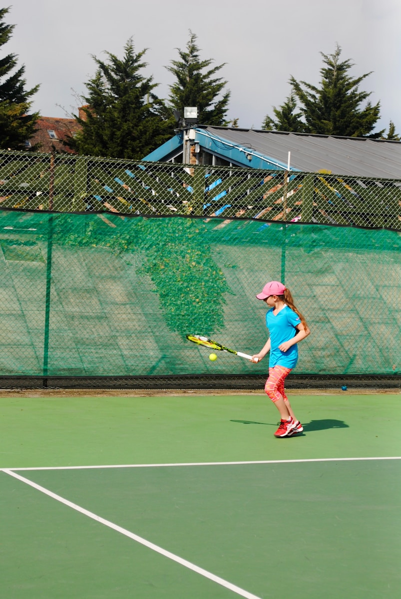 a young girl playing tennis on a tennis court