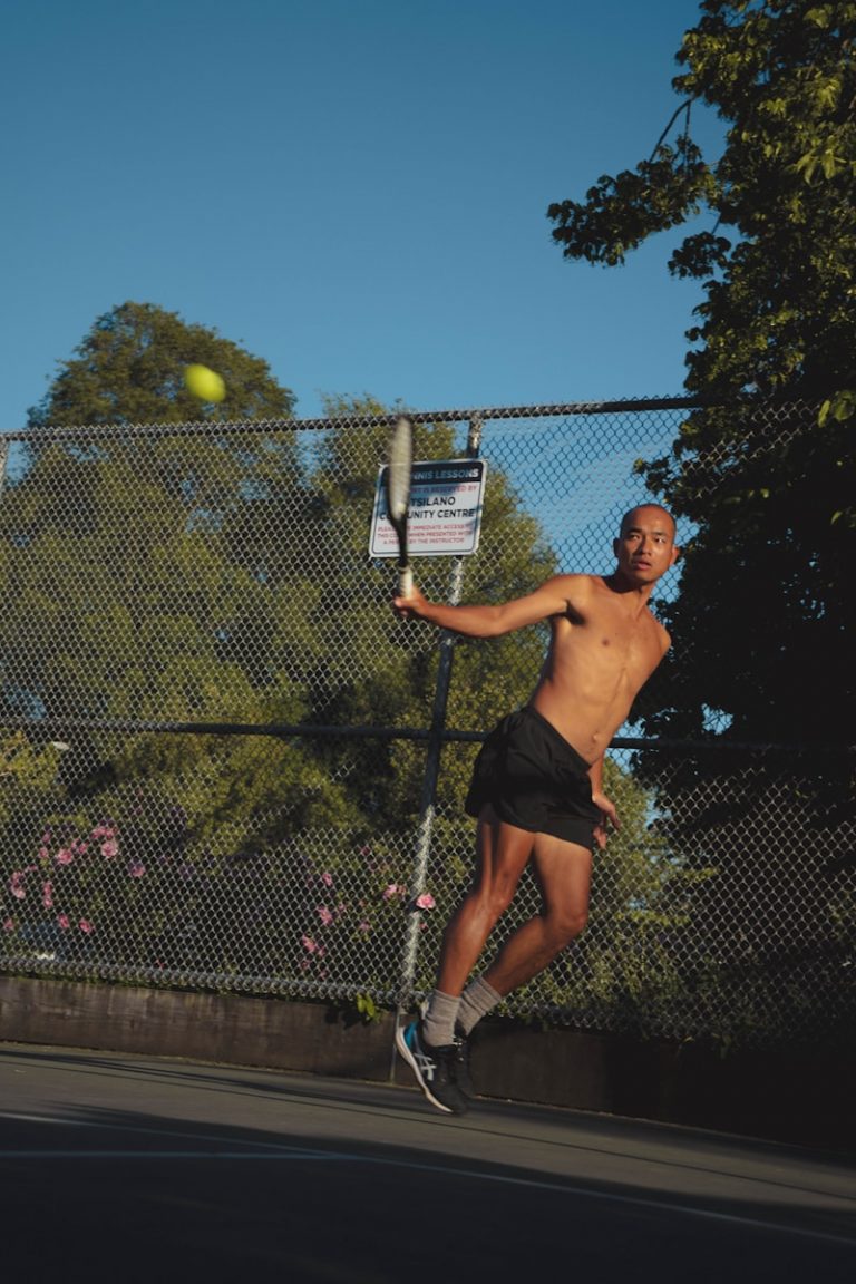 A shirtless man playing tennis on a tennis court