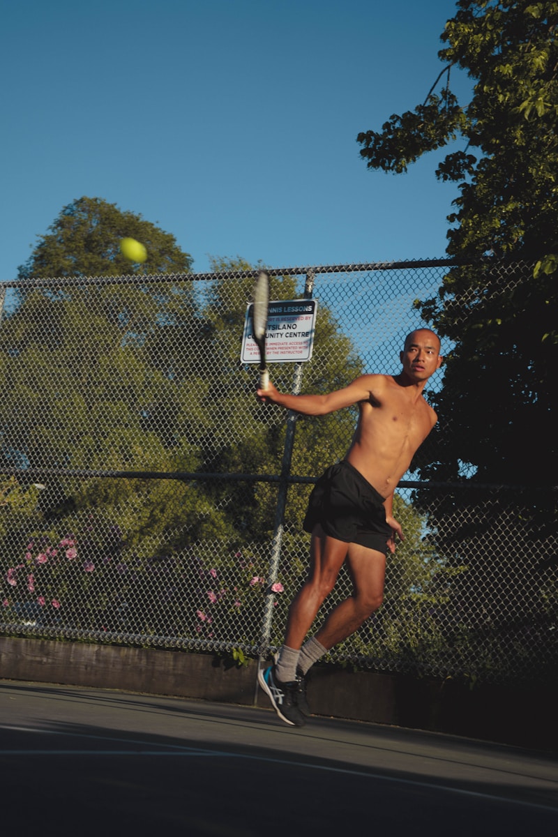A shirtless man playing tennis on a tennis court